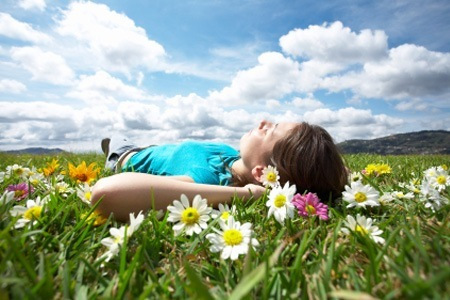 woman laying on back in a grassy field